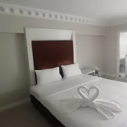 Pokój hotelowy z łóżkiem ozdobionym ręcznikami w kształcie łabędzi. Takie detale mogą świadczyć o dbałości o klienta, co jest pomocne, gdy szukasz, jak znaleźć tani nocleg.