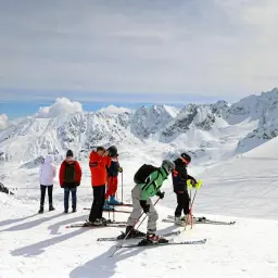 Ludzie na nartach na ośnieżonym stoku Kasprowego Wierchu, podziwiający majestatyczne Tatry.