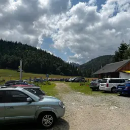 Kasprowy Wierch parking pełen samochodów pod malowniczym, zalesionym zboczem.