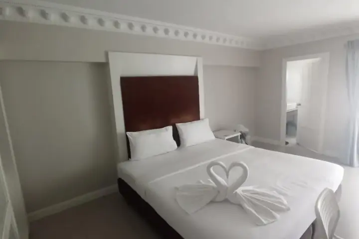 Pokój hotelowy z łóżkiem ozdobionym ręcznikami w kształcie łabędzi. Takie detale mogą świadczyć o dbałości o klienta, co jest pomocne, gdy szukasz, jak znaleźć tani nocleg.